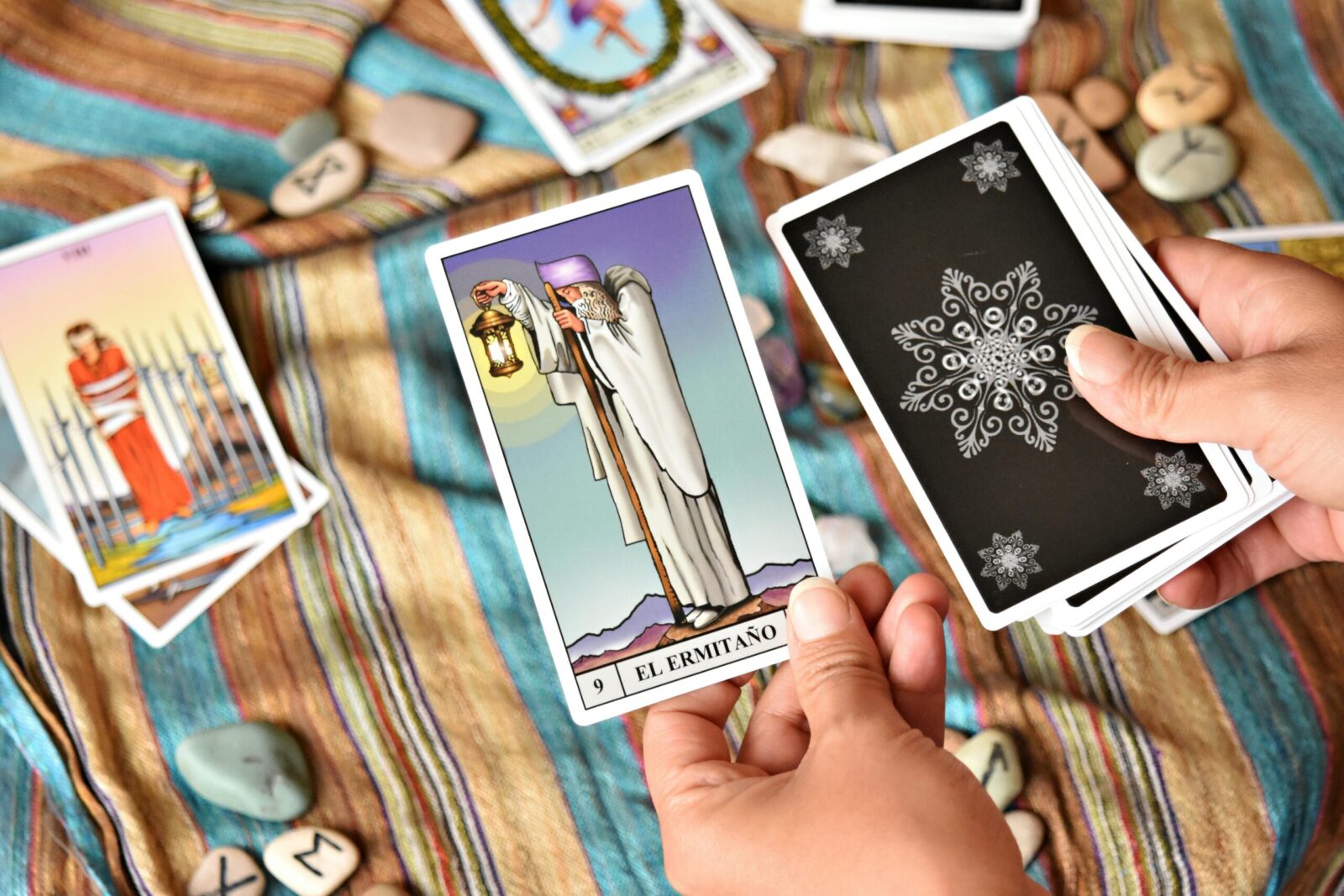 Vibrant tarot card reading scene with colorful deck and stones on patterned fabric.